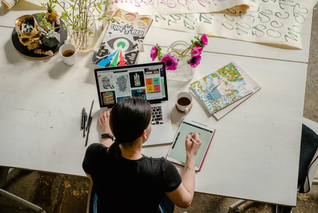 photo of woman writing on tablet computer while using laptop - everyday decision challenges