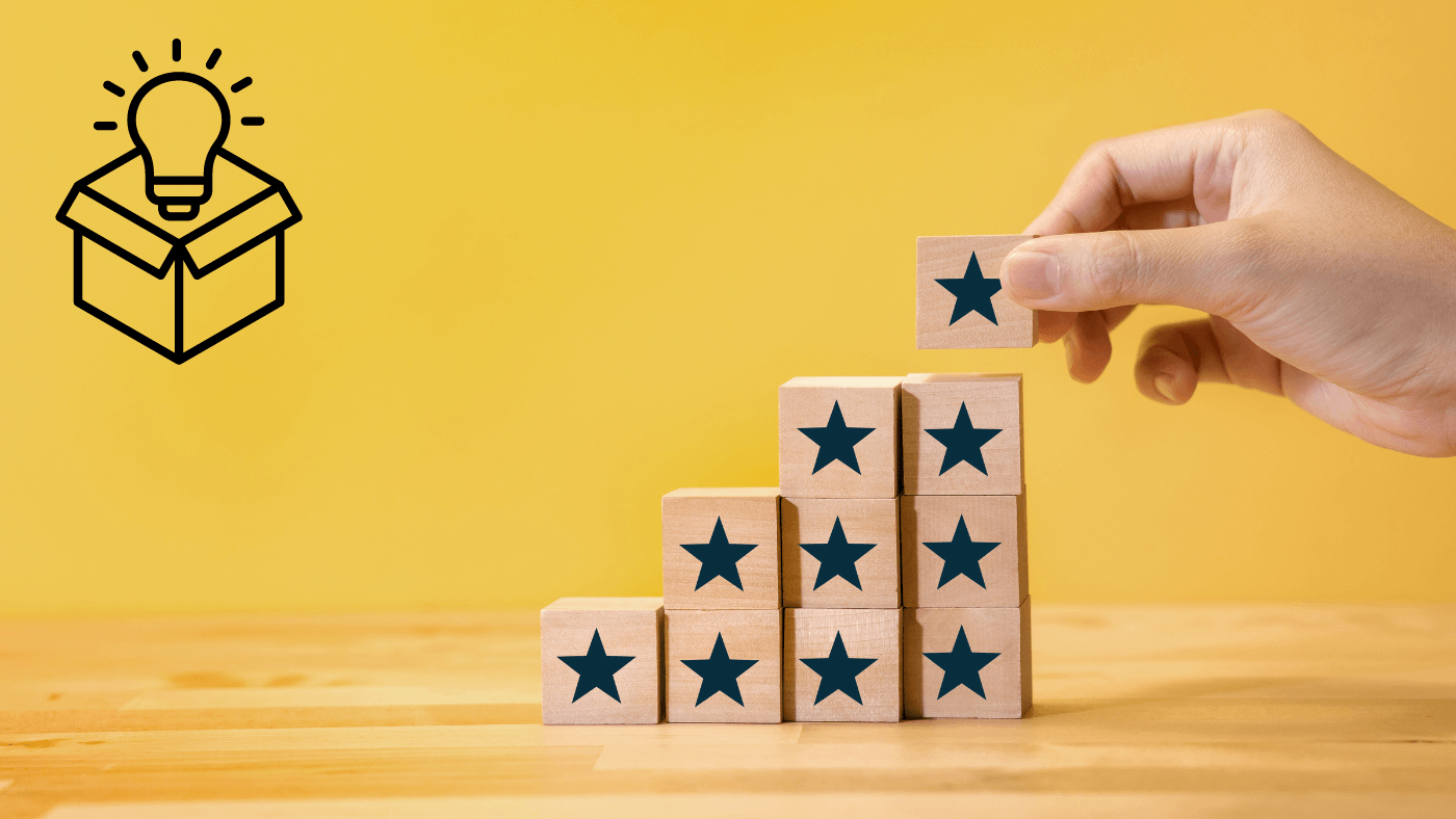 Hand stacking wooden blocks with stars, beside a lightbulb icon coming out of a box
