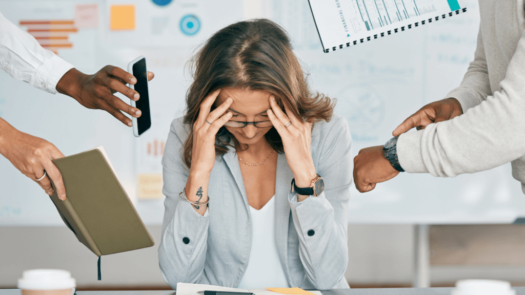 Woman holding her head due to stress of not able to focus on work because of multiple interruptions. Why lose focus at work.
