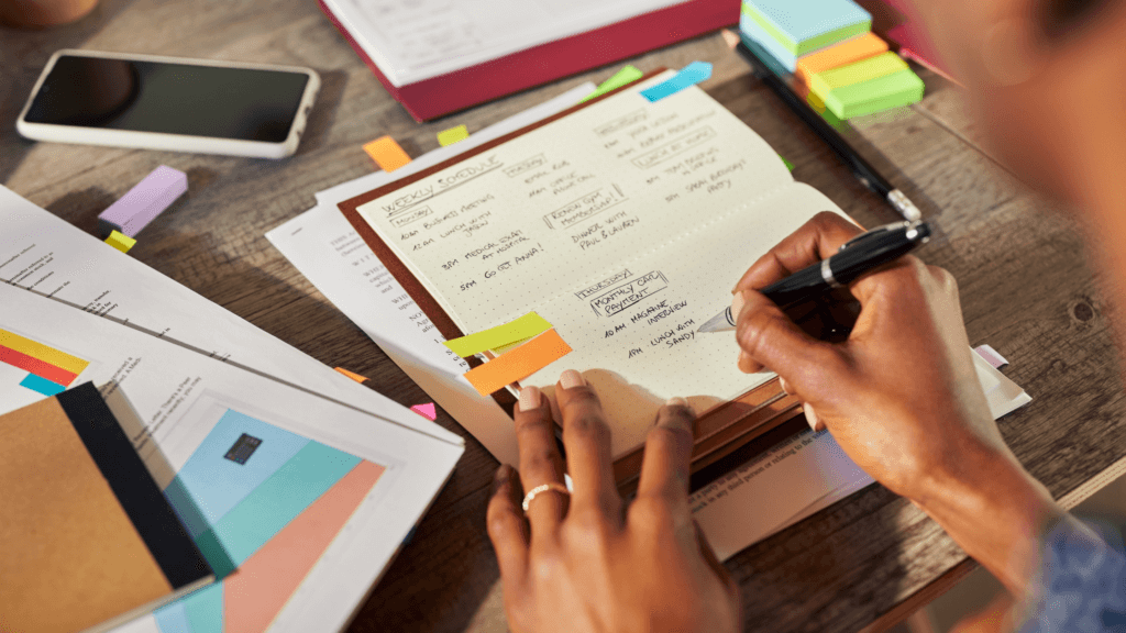 Closeup view of women planning her week in advance using colored sticky notes. Customized planners for productivity