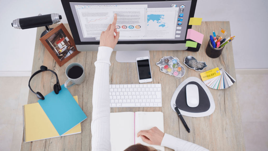 The female points her finger at the computer in her workspace with tools and documents. Productivity systems for professionals.